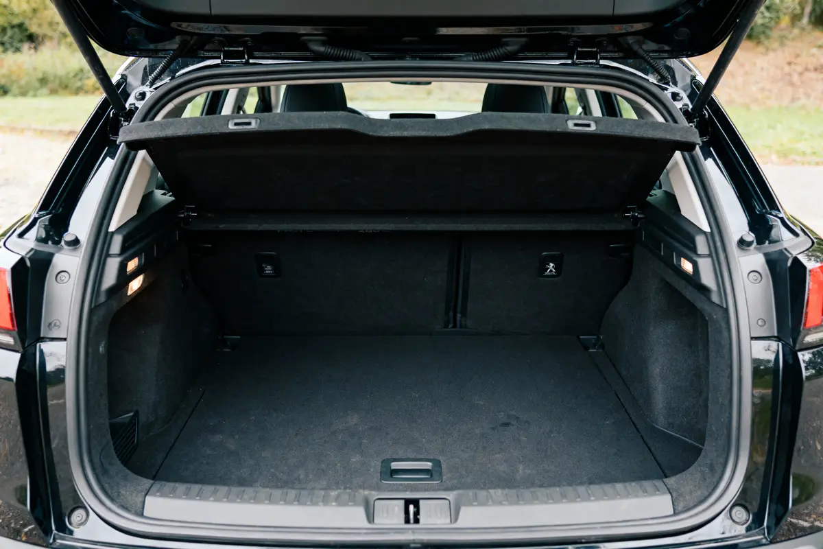Coffre de voiture ouvert, spacieux et vide, avec intérieur noir, par journée extérieure ensoleillée.