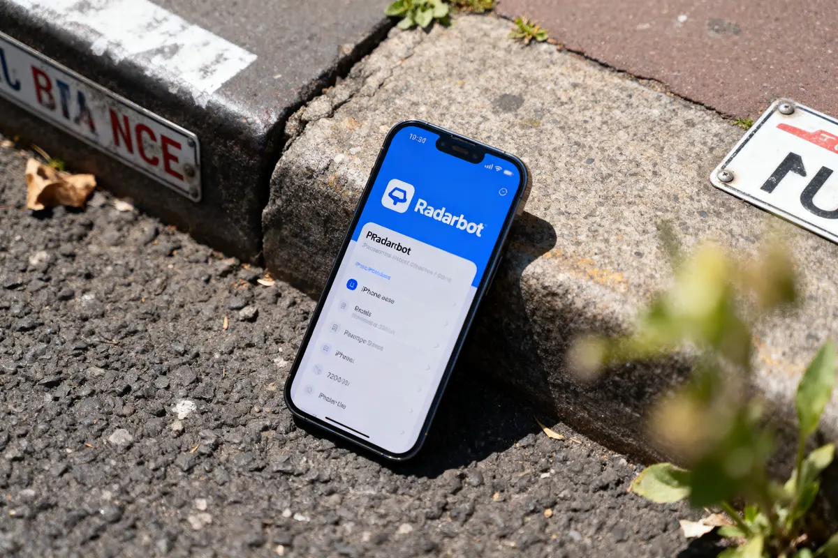 Smartphone affichant l'application Radarbot, posé sur le trottoir à côté d'une plaque de rue.