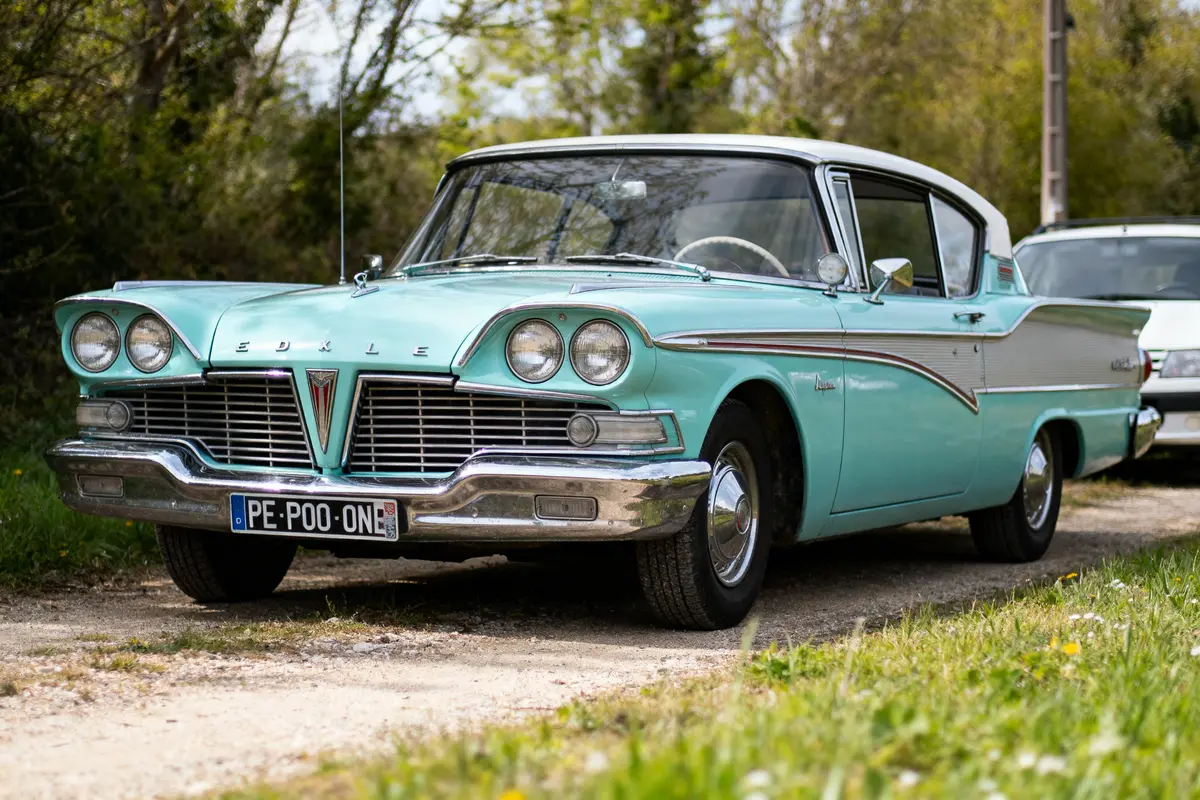Voiture vintage Edsel turquoise garée sur un chemin. Arrière-plan verdoyant avec un autre véhicule.