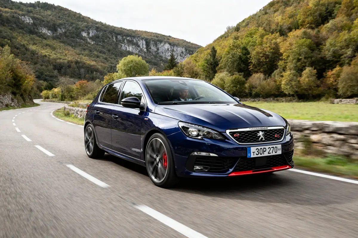 Voiture Peugeot 308 GTi bleue roulant sur route sinueuse en pleine nature