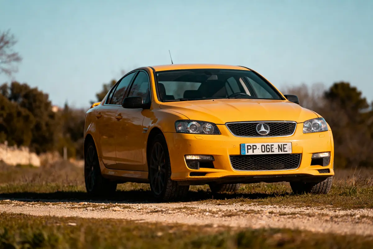 Voiture jaune stationnée sur un chemin rural avec code couleur de voiture distinctif