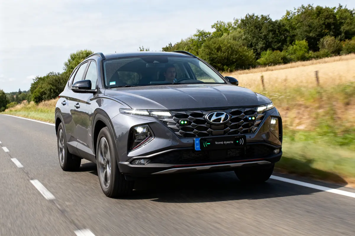 SUV Tucson hybride gris conduit avec régulateur intelligent sur route rurale