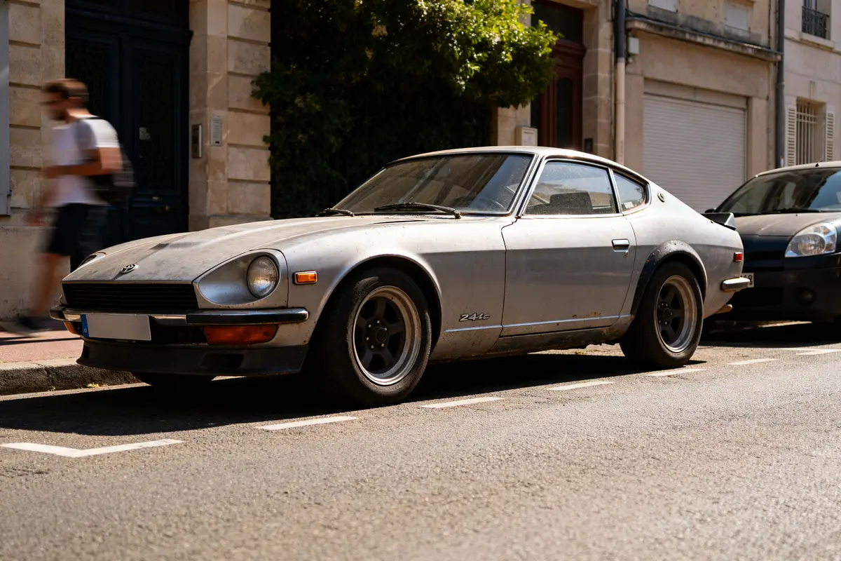 Voiture Datsun 240z automatic grise stationnée dans une rue ensoleillée