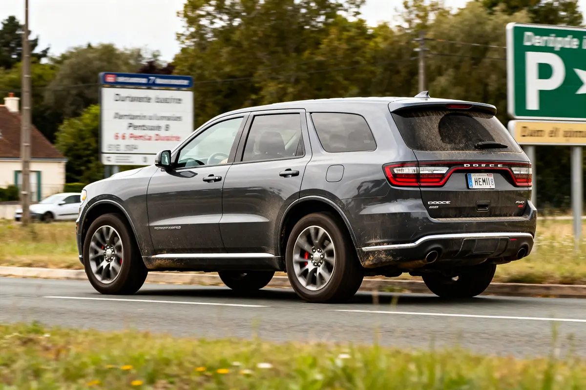 Dodge Durango gris sur route près de panneaux routiers et végétation en arrière-plan