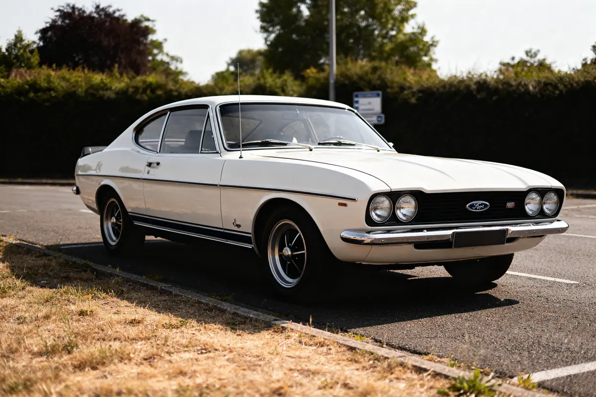 Voiture classique blanche Ford Capri 1970 garée sur un parking ensoleillé