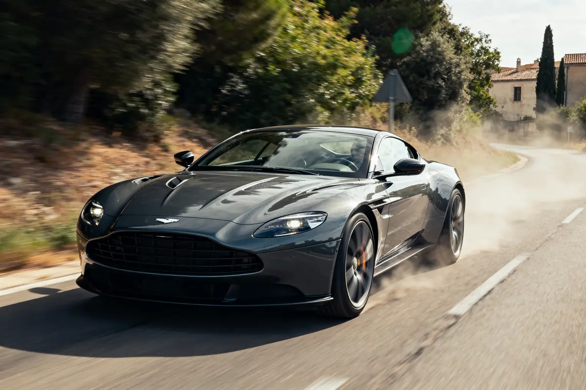 Voiture sportive noire roulant sur route de campagne en France évoquant des supercars.