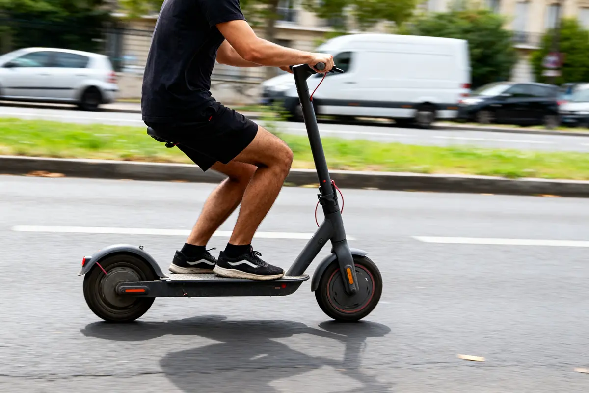 Personne roulant sur une trottinette électrique en ville, apprendre comment conduire une trottinette électrique