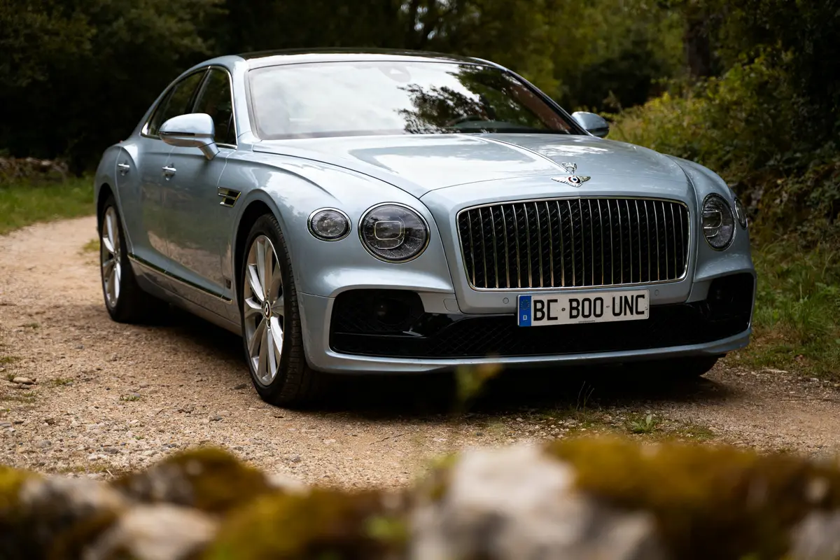 Berline grise de luxe sur chemin forestier de la marque de voiture Bentley