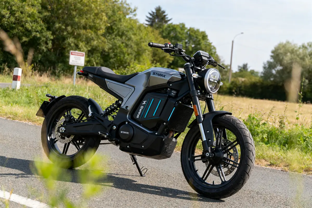 Moto électrique Starkvarg sur route de campagne ensoleillée avec végétation luxuriante autour